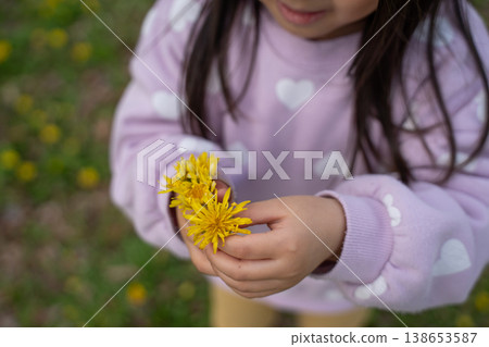 A child's hand handing over a yellow flower 138653587