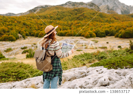 Young woman hiking in autumn landscape with a map. Travel, nature concept. Active lifestyle. Young woman hiking in autumn landscape with a map. Travel, nature concept. Active lifestyle. 138653717