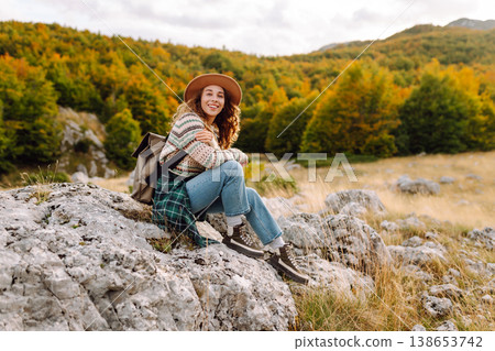 Young woman enjoys sunny afternoon in mountains while sitting on rocks. Tourism. Active lifestyle. Young woman enjoys sunny afternoon in mountains while sitting on rocks. Tourism. Active lifestyle. 138653742