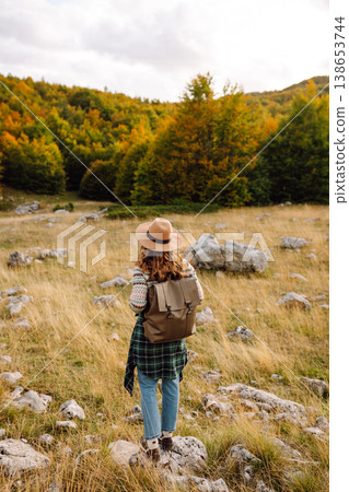 Young woman enjoys sunny afternoon in mountains while sitting on rocks. Tourism. Active lifestyle. Young woman enjoys sunny afternoon in mountains while sitting on rocks. Tourism. Active lifestyle. 138653744
