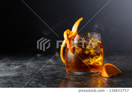 Whiskey with ice in a fogged up glass on a black stone table. Whiskey with ice in a fogged up glass on a black stone table. 138653757