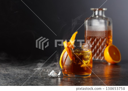 Old-fashioned cocktail in a fogged up glass on a black stone table. Old-fashioned cocktail in a fogged up glass on a black stone table. 138653758