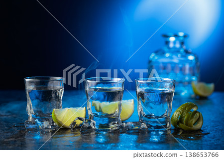 Vodka with lime slices on a blue background. Vodka with lime slices on a blue background. 138653766