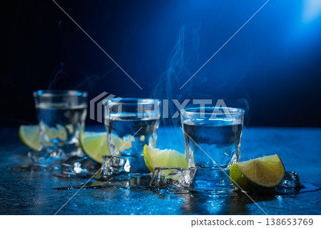 Vodka with lime slices on a black stone table. 138653769