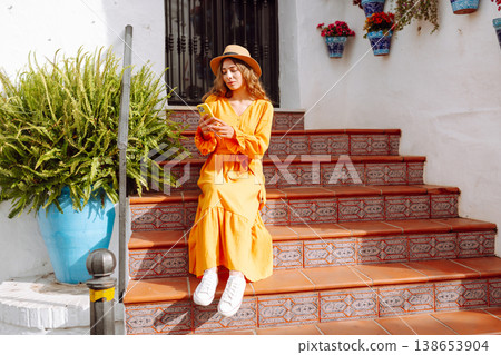 Female traveler in a beautiful yellow dress is sightseeing in European cities. Travel, tourism 138653904