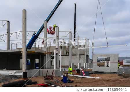 Cranes and workers assembling steel frame on concrete structure at industrial construction site Cranes and workers assembling steel frame on concrete structure at industrial construction site 138654041
