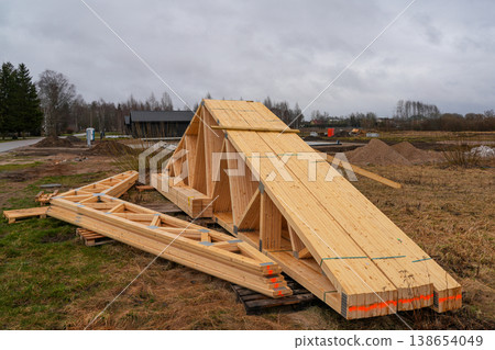 Stacked timber roof trusses and beams prepared on rural construction site for house building project 138654049