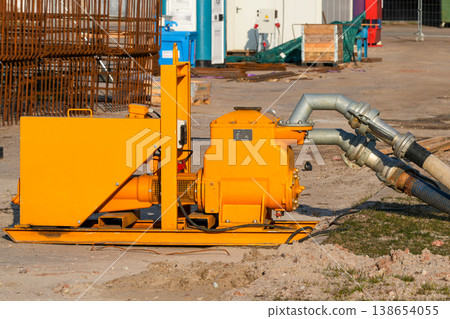 Close-up of industrial dewatering pump and hose system at construction site excavation area Close-up of industrial dewatering pump and hose system at construction site excavation area 138654055