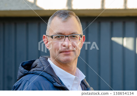 Man aged 51 wearing glasses standing outdoors against building background 138654134
