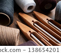 Elegant composition of wooden boat shuttles and spools of weaving yarn on a dark wooden table. Traditional textile tools and the craftsmanship of hand weaving 138654201