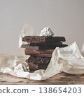 Stack of various chocolate bars including aerated dark and milk chocolate paired with gourmet truffles on parchment paper 138654203