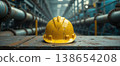 Worn yellow safety helmet in industrial pipeline facility 138654208