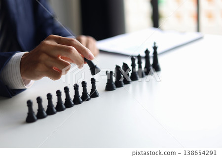 Businessman wearing suit, playing chess game. Business strategy, leadership, planning and management concept. 138654291
