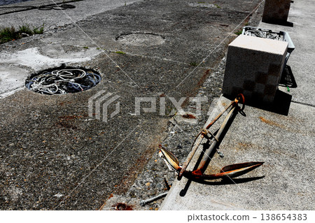 漁港碼頭上遺棄著一個鏽跡斑斑的舊錨和漁網繩。 漁港碼頭上遺棄著一個鏽跡斑斑的舊錨和漁網繩。 138654383