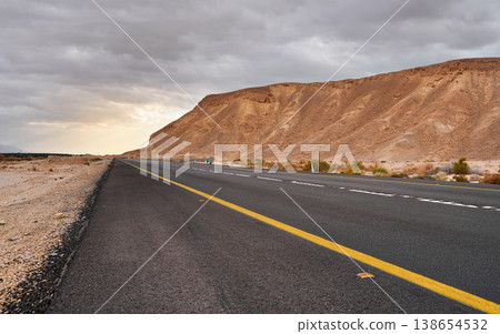 Modern asphalt highway leading through desert landscape in Southern region of Israel, cloudy sky above Modern asphalt highway leading through desert landscape in Southern region of Israel, cloudy sky above 138654532