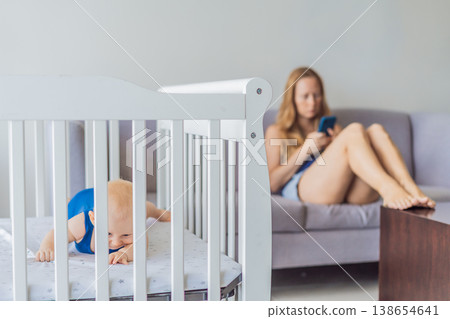 Very tired mother sitting by baby crib at home feeling exhausted. Sleep deprived mom caring for newborn at night. Parenting fatigue, motherhood stress, childcare and real family life concept Very tired mother sitting by baby crib at home feeling exhausted. Sleep deprived mom caring for newborn at night. Parenting fatigue, motherhood stress, childcare and real family life concept 138654641