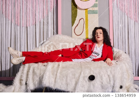 Modern person in red lounging attire resting on plush furniture Modern person in red lounging attire resting on plush furniture 138654959