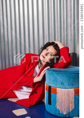 Colorful performer leaning on stool with intense gaze and bold makeup Colorful performer leaning on stool with intense gaze and bold makeup 138654991