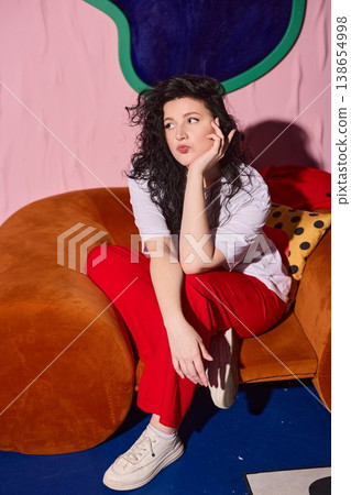 Woman in casual attire enjoys tranquil moment on vibrant furniture Woman in casual attire enjoys tranquil moment on vibrant furniture 138654998
