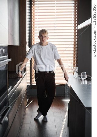 Casual male in vibrant contemporary kitchen showing thoughtful expression 138655050