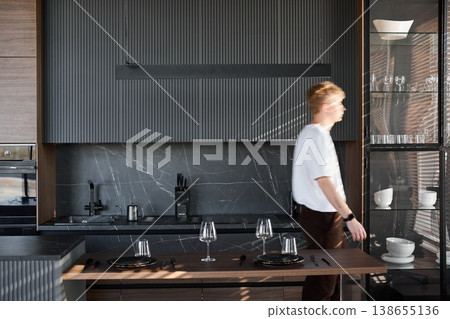 Seated man unwinding with drink beside reflective surfaces on island Seated man unwinding with drink beside reflective surfaces on island 138655136