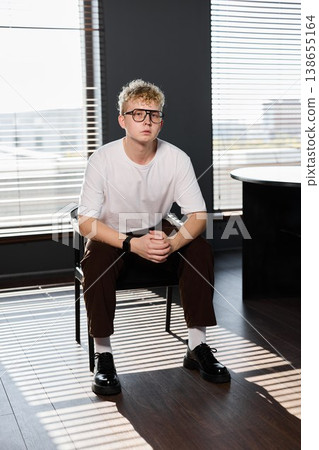 Junior professional seated thoughtfully in modern workspace environment 138655164