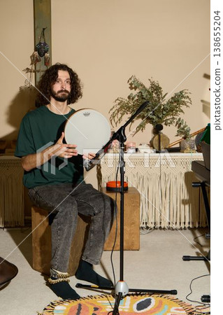 Chilledout performer holding drum during homely moment in natural light Chilledout performer holding drum during homely moment in natural light 138655204