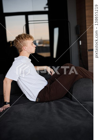 Tranquil scene of young man resting on sofa during sunny late afternoon Tranquil scene of young man resting on sofa during sunny late afternoon 138655219