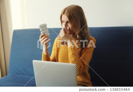 Sick woman suffers from a cold while working with laptop at home Sick woman suffers from a cold while working with laptop at home 138655464
