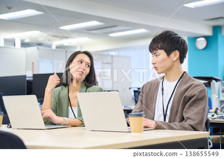 Businesswomen contemplating while working on their PCs side-by-side in a free-address office. Businesswomen contemplating while working on their PCs side-by-side in a free-address office. 138655549