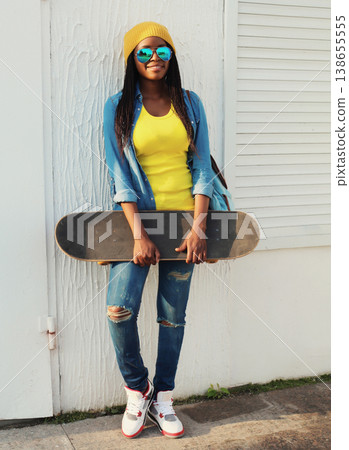 Stylish happy African young woman with skateboard, modern black teenage girl posing outdoors Stylish happy African young woman with skateboard, modern black teenage girl posing outdoors 138655555