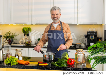 Middle-aged man cooking healthy soup on electric stove in home kitchen for diet nutrition lifestyle 138656221