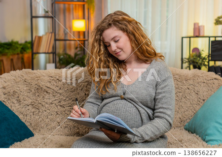 Pregnant young woman writing in diary to do list at home, thoughtful and focused, future planning 138656227