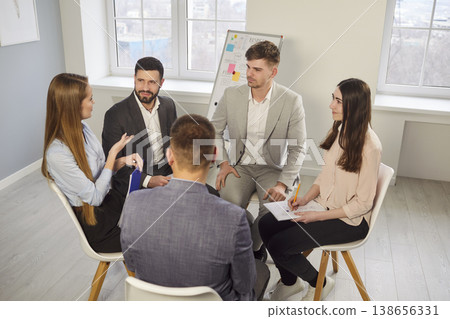 Group of young business professionals sitting in circle and sharing ideas during office team meeting 138656331