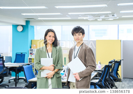 A smiling foreign businesswoman working on her laptop in a brightly lit office. A smiling foreign businesswoman working on her laptop in a brightly lit office. 138656378