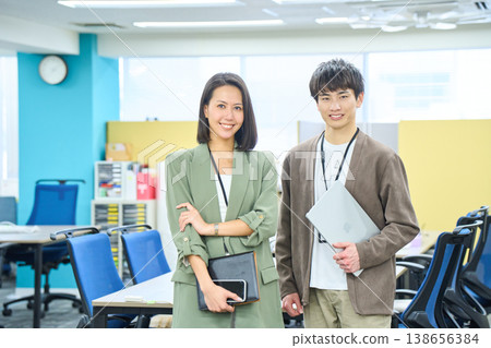 A smiling foreign businesswoman working on her laptop in a brightly lit office. A smiling foreign businesswoman working on her laptop in a brightly lit office. 138656384