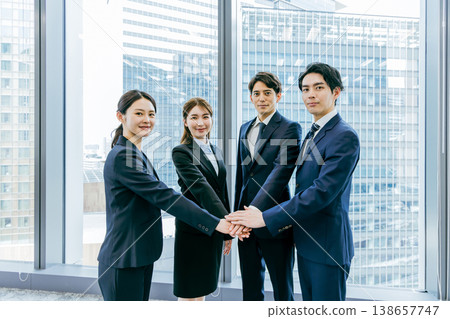 Business group standing in a circle with hands together Business group standing in a circle with hands together 138657747