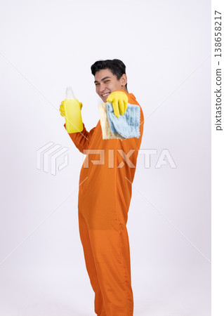 Happy maintenance worker in orange jumpsuit holding a spray bottle 138658217