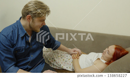 Man sitting by the bed supporting a sick woman at home Man sitting by the bed supporting a sick woman at home 138658227
