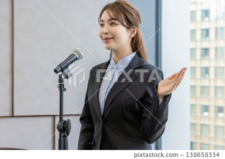 A white woman speaking into a microphone at a workshop. A white woman speaking into a microphone at a workshop. 138658334
