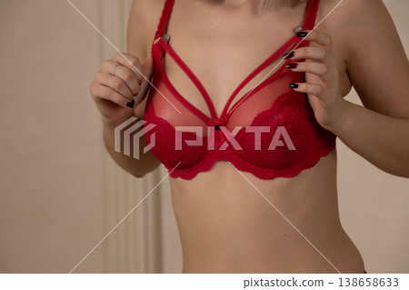 Young woman adjusting red lace bra in studio 138658633