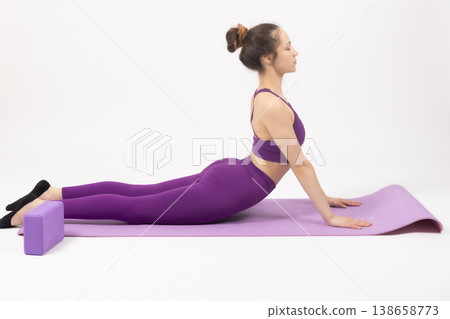 Athletic woman in purple outfit doing yoga stretch on mat 138658773