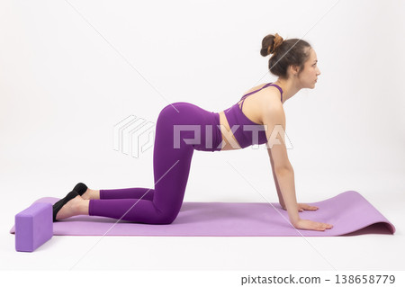 Young woman in purple sportswear doing yoga on mat 138658779