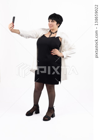 Stylish woman taking a selfie with her smartphone in studio Stylish woman taking a selfie with her smartphone in studio 138659022