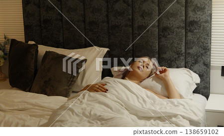 Happy woman waking up and stretching in bed in the morning 138659102