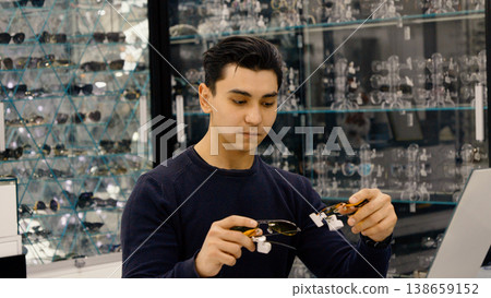Young man examining optical frames in a store 138659152