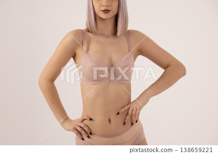 Beautiful woman in beige lingerie posing with hands on hips Beautiful woman in beige lingerie posing with hands on hips 138659221