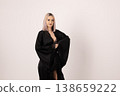 Elegant woman in black attire posing against light background 138659222