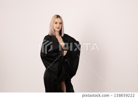 Elegant woman in black attire posing against light background Elegant woman in black attire posing against light background 138659222