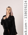 Confident blonde woman in black clothing posing in studio 138659224